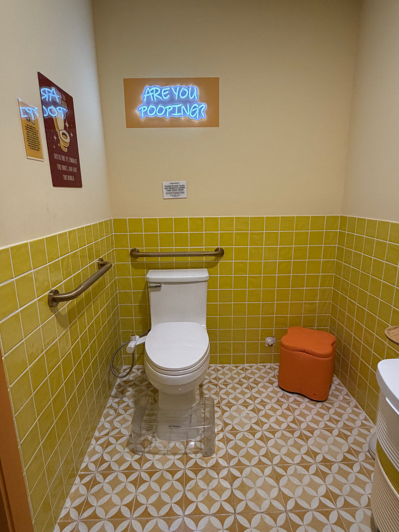 Bathroom with yellow tiled walls, a toilet, and decorative elements.