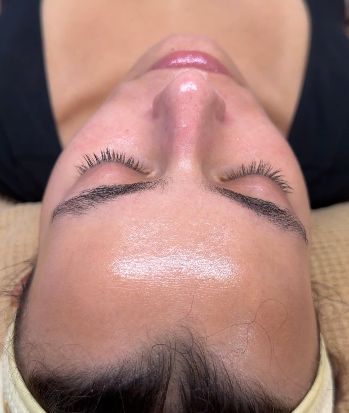 Close-up of a person receiving a facial treatment with a white cream on their face.