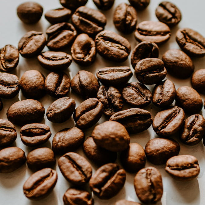 Coffee beans arranged in a circular pattern on a light background