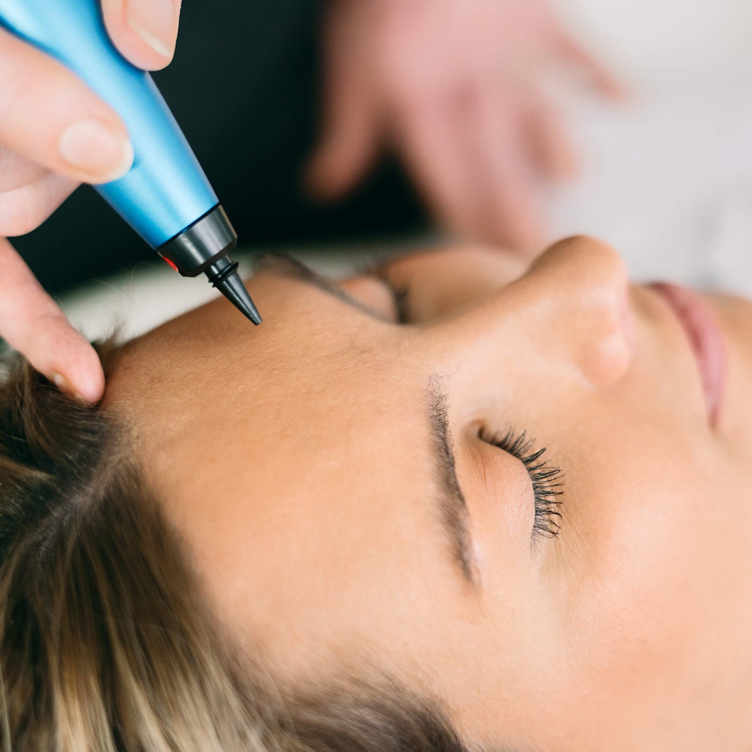 Person receiving a facial treatment with a blue device on their face.