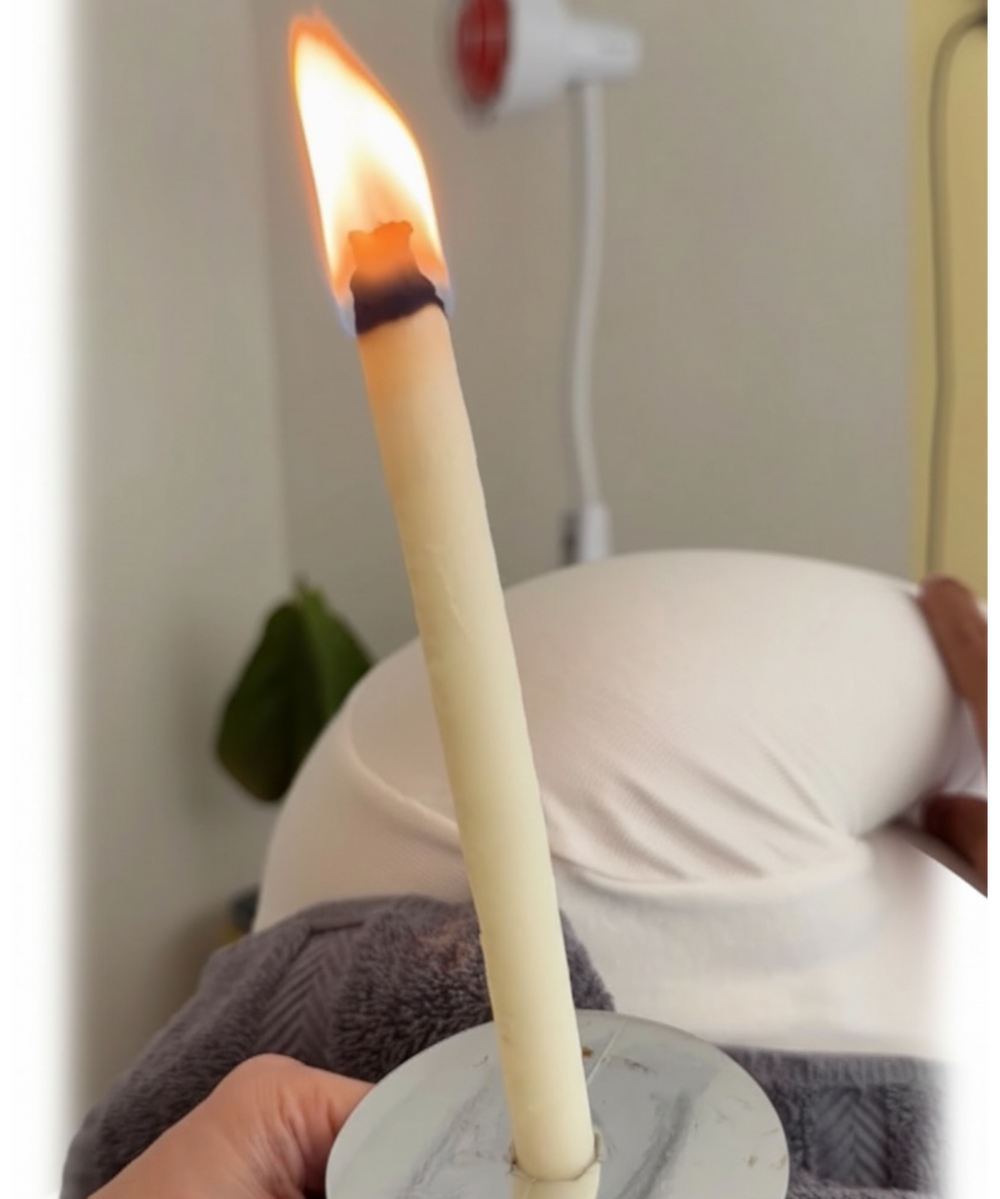 Hand holding a lit candle with a blurred background