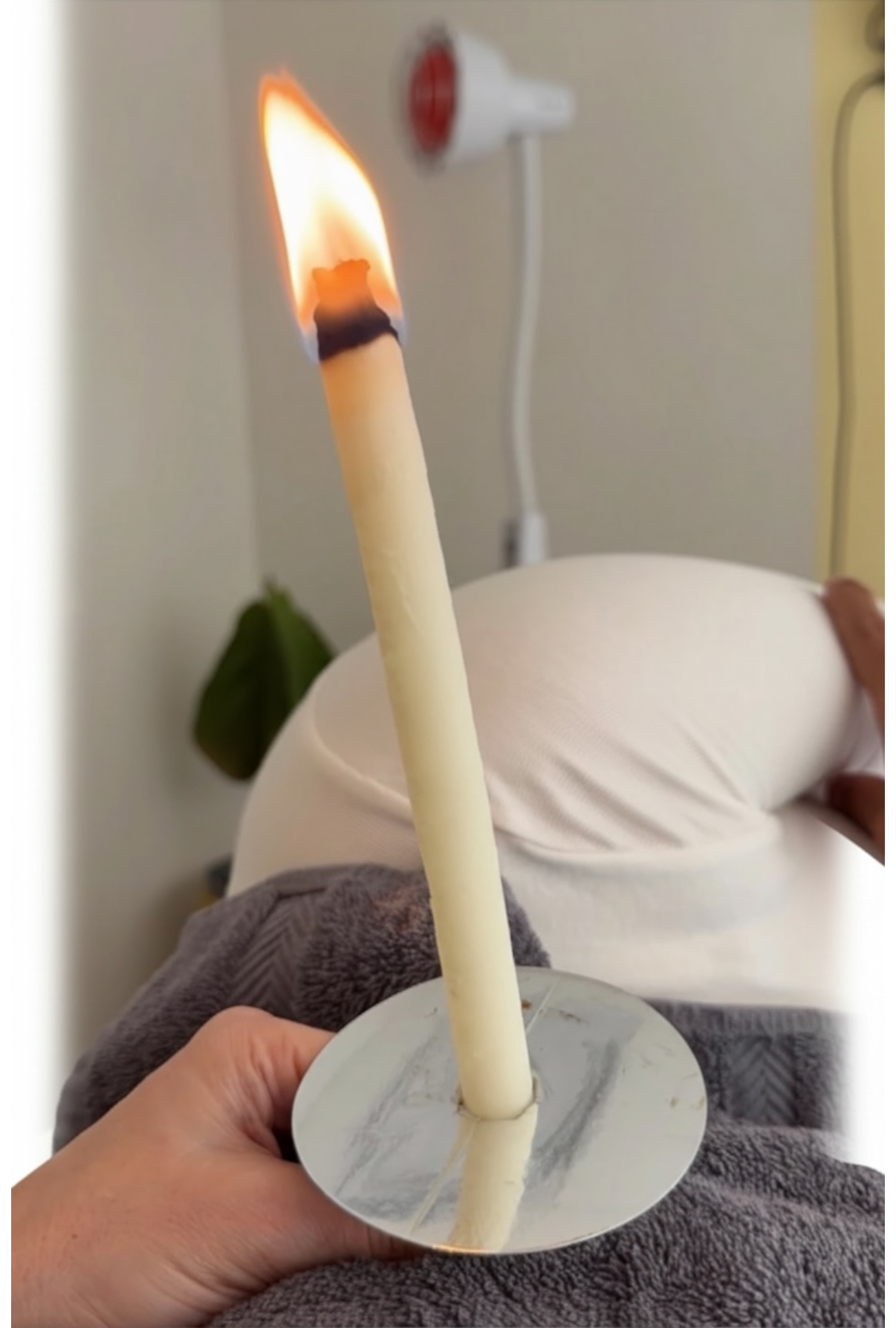 Hand holding a lit candle with a blurred background