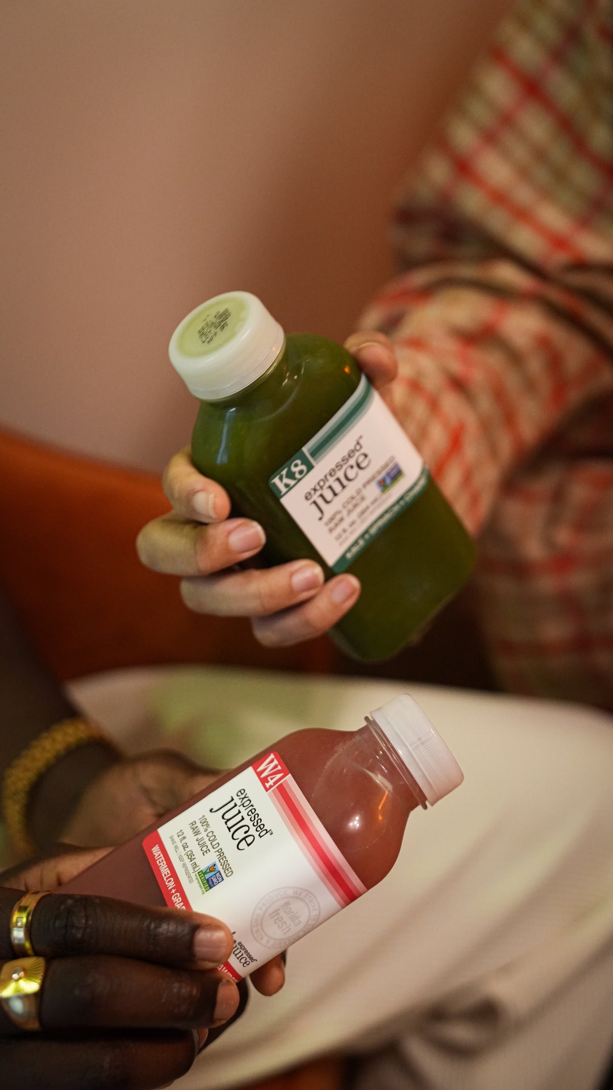 Two bottles of K's Tor夫儿 juice held by a person, one green and one red.