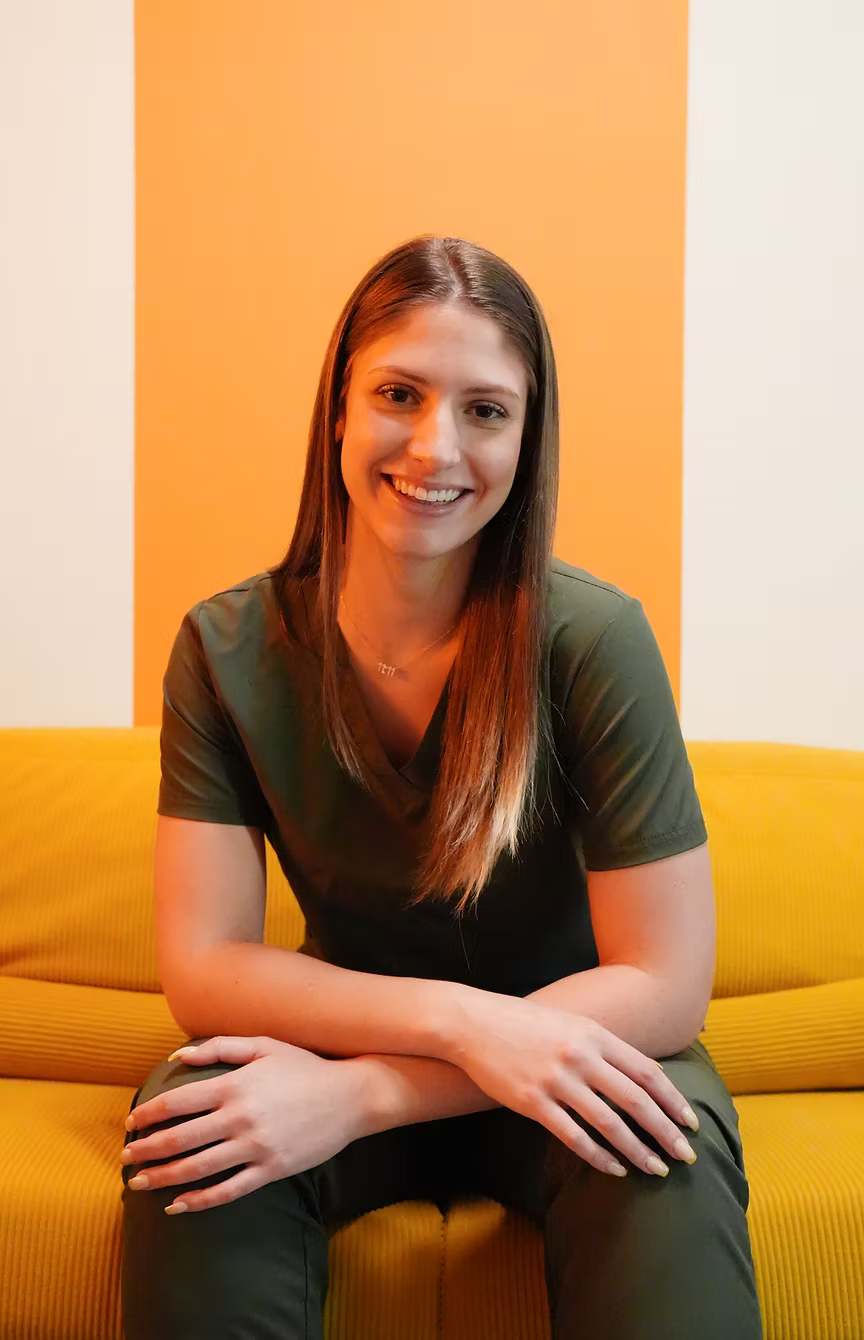 Woman sitting on a yellow couch against an orange and beige wall