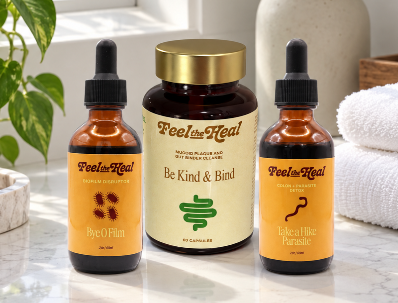 Three amber glass bottles and a central jar from Peola Real are arranged on a white marble countertop in a bright bathroom setting. The products have cream and orange labels, with dropper tops on two bottles and a gold cap on the center jar.