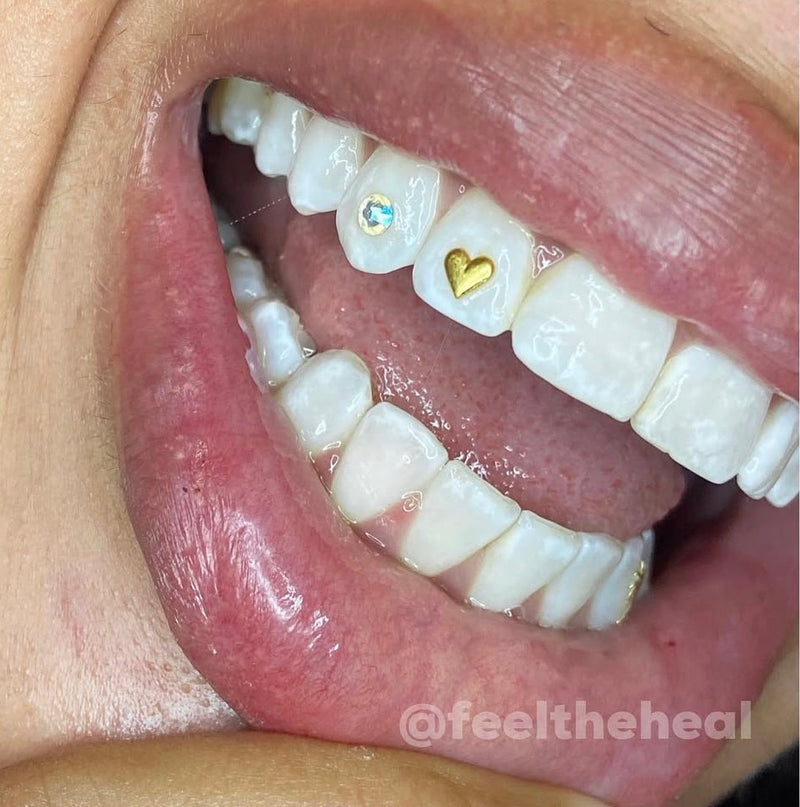 Close-up of a mouth with decorative teeth, featuring a heart and a diamond.