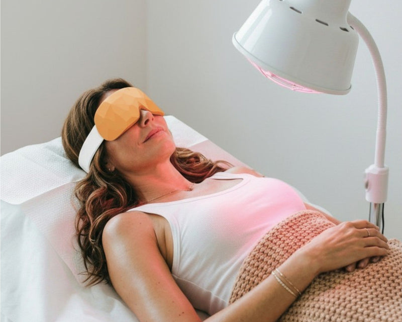 Woman receiving red light therapy with a lamp above her